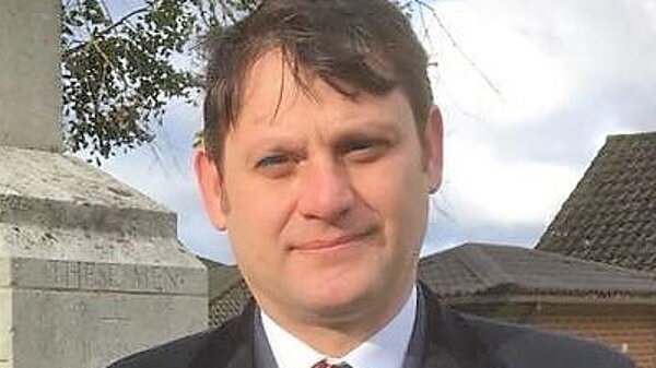 Richard Howard stands beside a war memorial